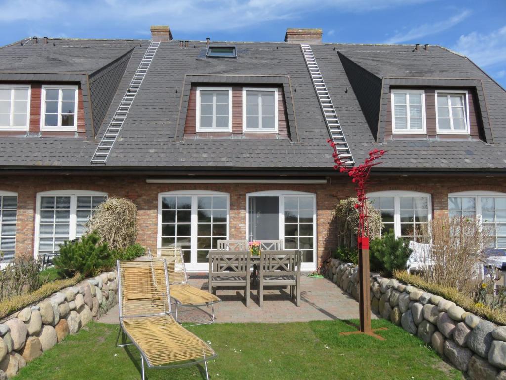 a house with two chairs and a table in the yard at Wünderschöner Hausteil Mit Garten in Archsum
