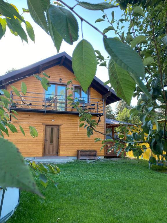 a large wooden house with a porch and green grass at Center Cottage Чан in Slavske