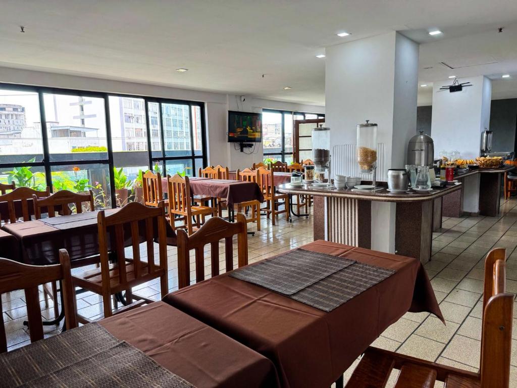 an empty restaurant with tables and chairs and windows at Stratus Centro Hotel in Volta Redonda