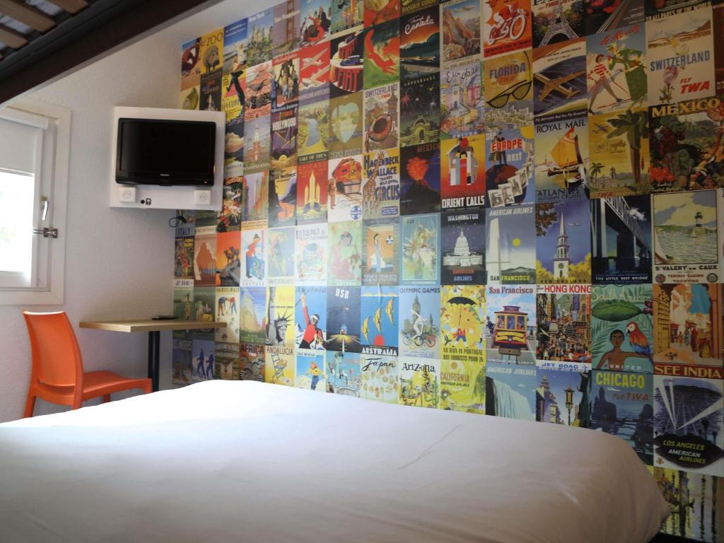 a bedroom with a bed and a wall covered in posters at hotelF1 Orange Centre Echangeur A7 A9 in Orange