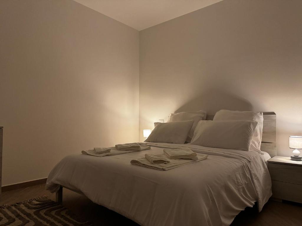 ein Schlafzimmer mit einem Bett mit weißen Laken und Kissen in der Unterkunft Ulisse Fashion Suites - Ecosole Real Estate in Serravalle Scrivia