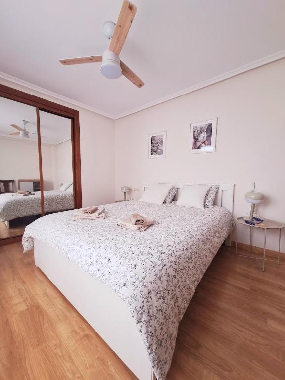 a white bedroom with a bed and a ceiling fan at Jona Candás Asturias in Candás