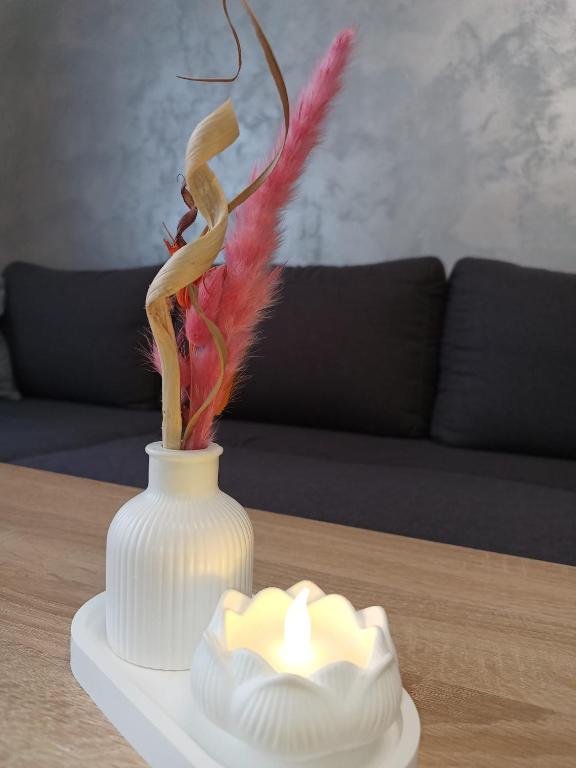 a white vase sitting on a table with a candle at Apartament Royal in Şelimbăr