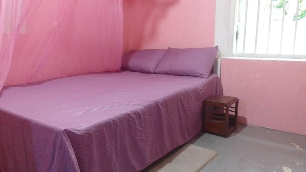 ein rosa Schlafzimmer mit einem Bett mit einer lila Decke in der Unterkunft villa Haborend in Galle