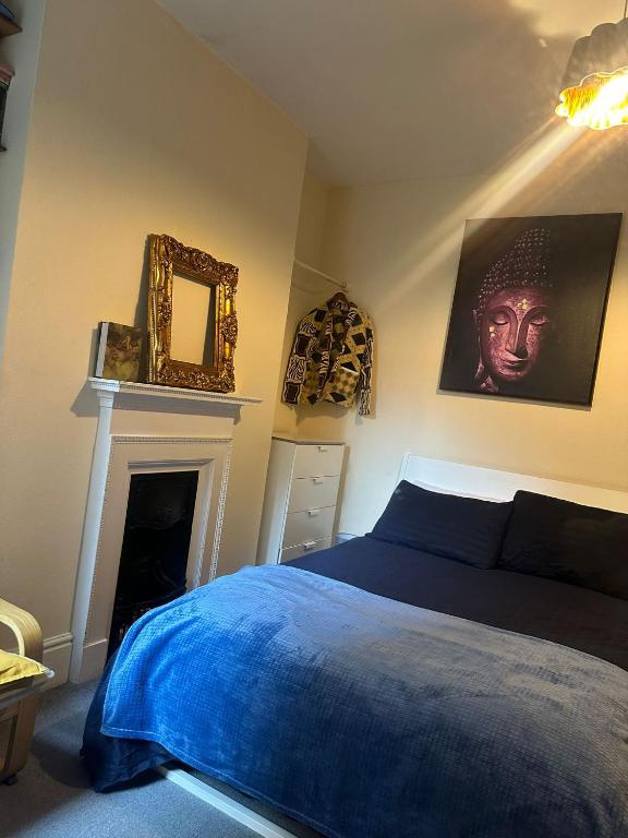 a bedroom with a blue bed and a fireplace at Effra Mansions in London
