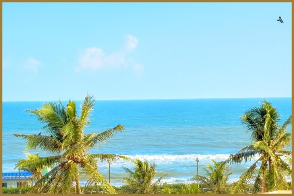 two palm trees on a beach with the ocean at Rooftop Sea View Marine Drive Road Duren- Beach-Resort # Jagannath Temple #Fully Air Condition with All Premium Rooms With Attached #Balcony Free Wifi & Lift Facilities- Top Rated Hotel in Puri