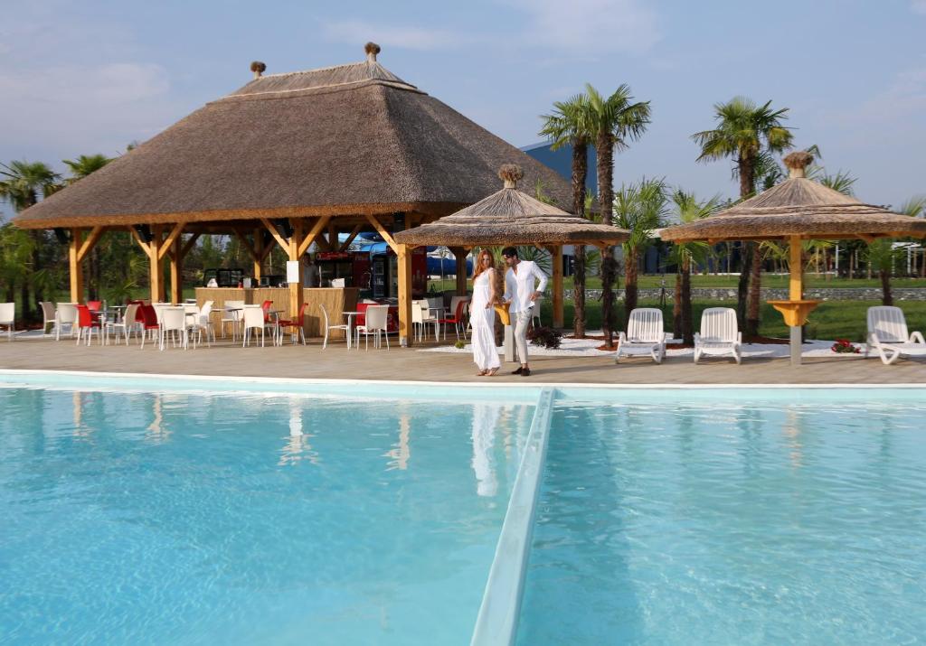 a couple standing next to a swimming pool at a resort at Mjus Resort & Thermal Park in Körmend