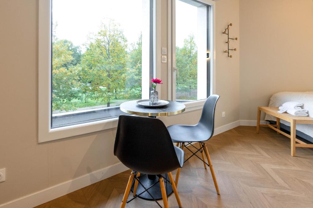 une pièce avec une table et deux chaises et une fenêtre dans l'établissement Appart Hôtel Coraline - Genas Lyon Eurexpo, à Genas