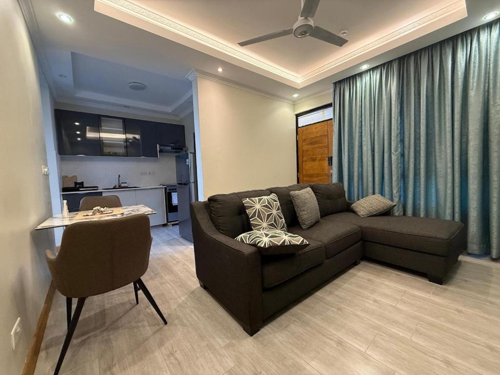 un salon avec un canapé marron et une cuisine dans l'établissement BenRoche place, à Kilifi