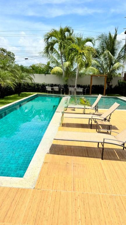 a large swimming pool with benches and palm trees at Guarajuba Acqua 103 in Camacari