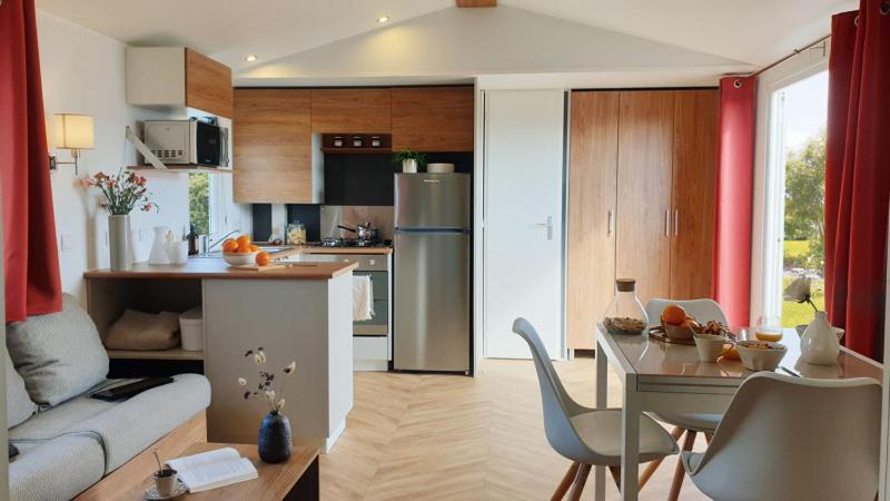 eine Küche und ein Wohnzimmer mit einer Couch und einem Tisch in der Unterkunft Mobil-home 8 personnes camping PONT AVEN - WIFI GARANTIE-grande terrasse-lave linge in Pont-Aven