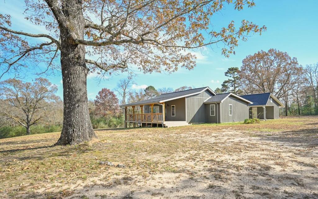 a house on a field with a tree at Three Oaks in Mena