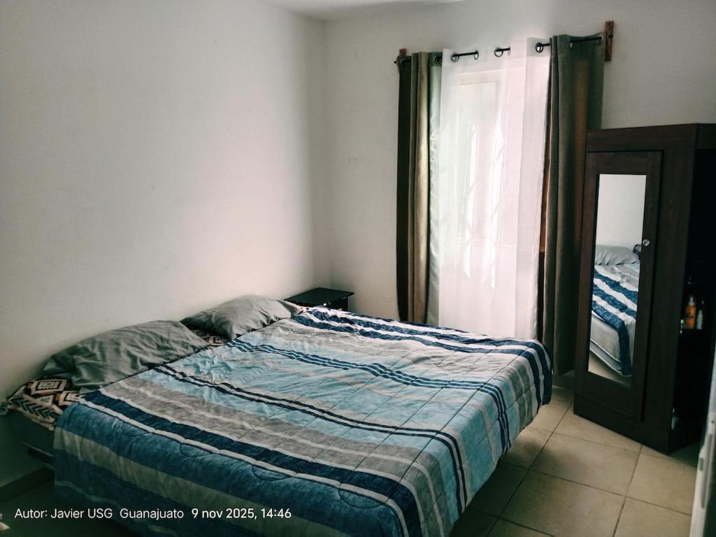 Schlafzimmer mit einem Bett, einem Fenster und einem Spiegel in der Unterkunft Casa Bellas Artes de 2 pisos en Fracc Privado in Irapuato