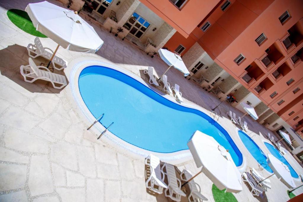 Banī Ghālibにあるكمبوند دلتا ستارزのパラソルと椅子付きのスイミングプールのオーバーヘッドビュー
