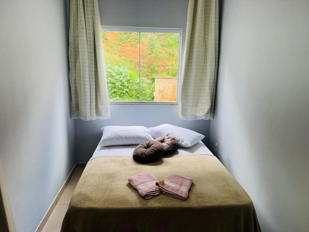 - un lit dans une chambre avec une fenêtre et 2 serviettes dans l'établissement Casa próxima ao centro a 3 min de carro, à São Lourenço