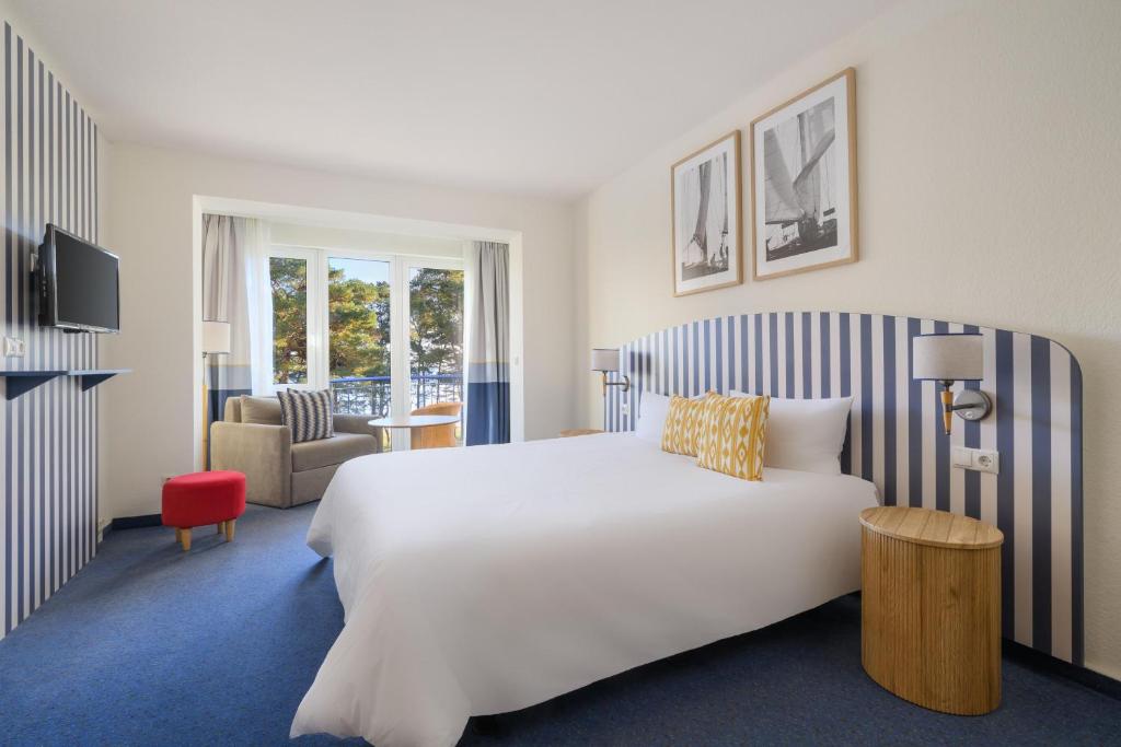 a hotel room with a large white bed and a chair at IFA Rügen Hotel & Ferienpark in Binz