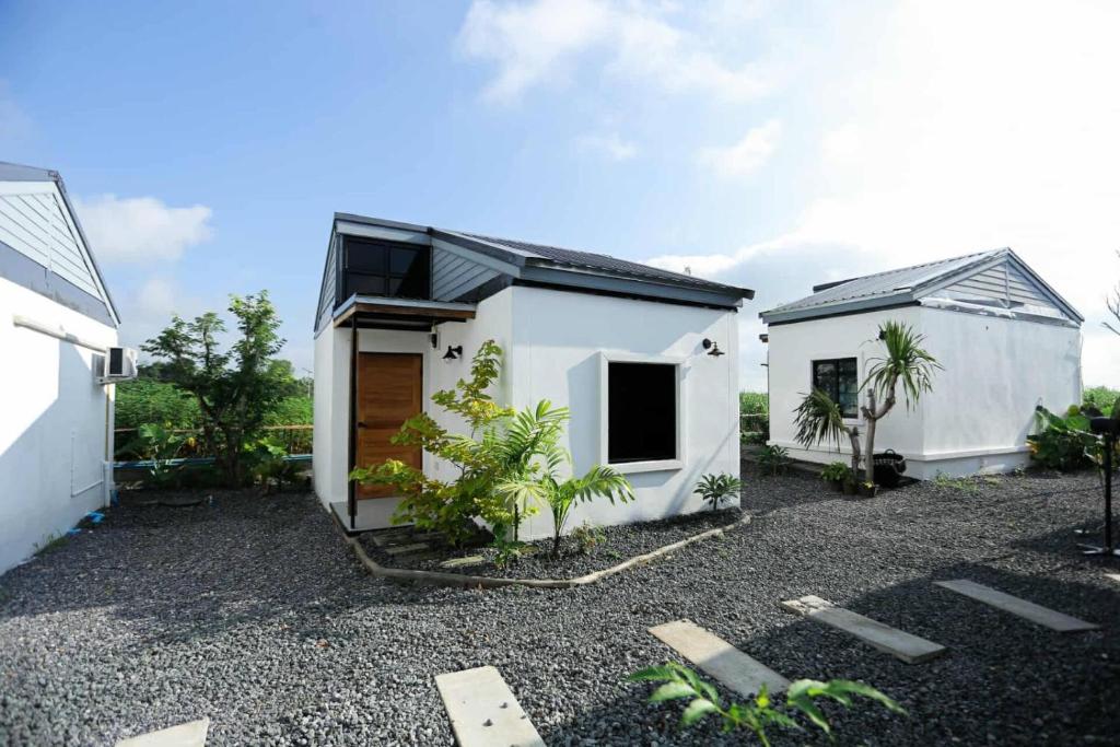 ein weißes Haus mit einer Garage neben einem Gebäude in der Unterkunft Wasana Village Phutoei in Ban Phu Toei