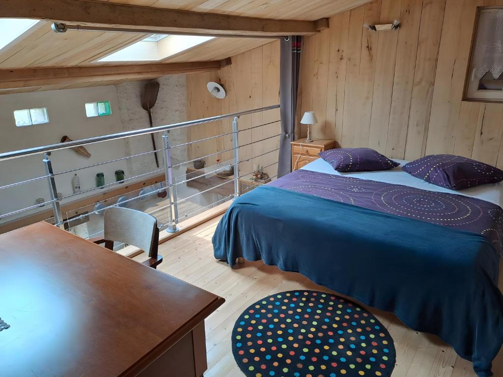 ein Schlafzimmer mit einem Bett, einem Schreibtisch und einem Tisch in der Unterkunft Gite L'Etable in Saint-Hilaire-la-Palud