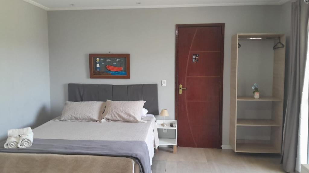 Un dormitorio con una cama y una puerta roja. en Pousada Canoa dos Anjos suítes, en Arraial do Cabo