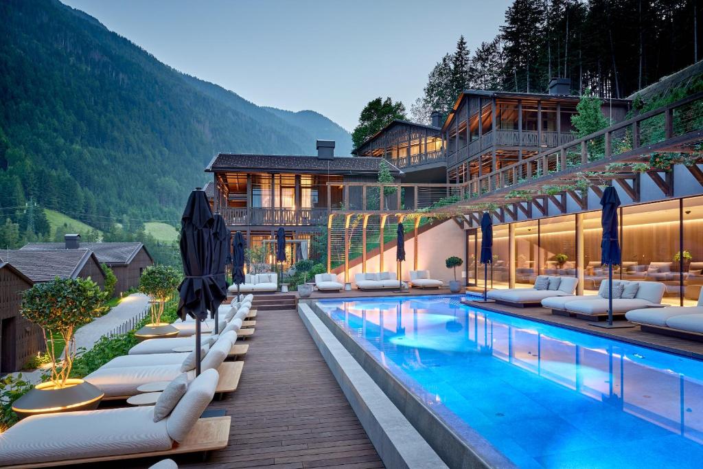 ein Hotel mit einem Swimmingpool mit Liegestühlen in der Unterkunft AMONTI Chalets in Mühlen in Taufers