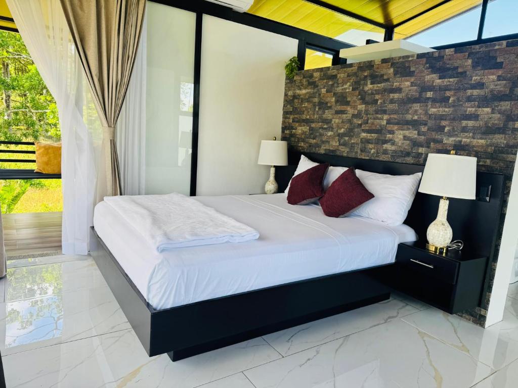 a bedroom with a bed with white sheets and red pillows at Cabañas La Hermosa #2 in Guápiles