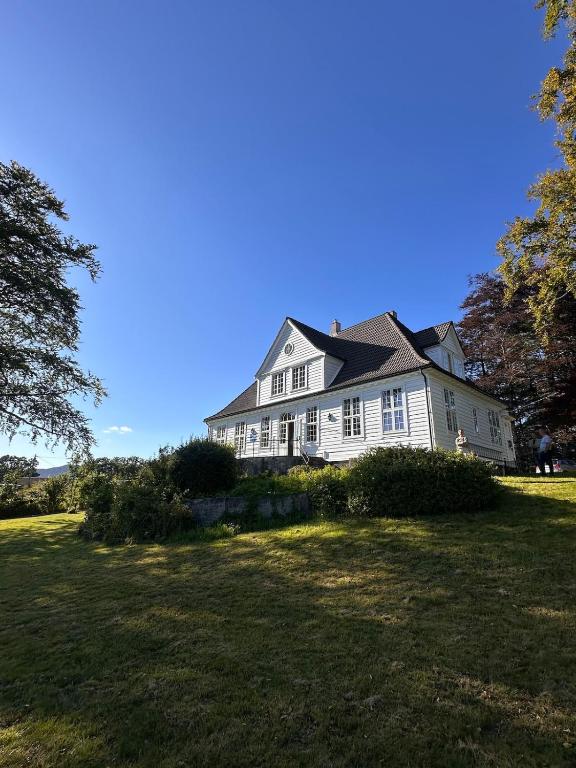 a large white house with a large yard at Historic villa with large garden in Stord