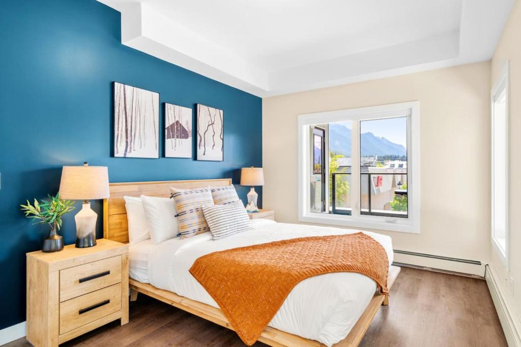 a bedroom with a bed with blue walls and a window at Stylish 2BR Golden Getaway with BBQ and Stunning Views in Golden