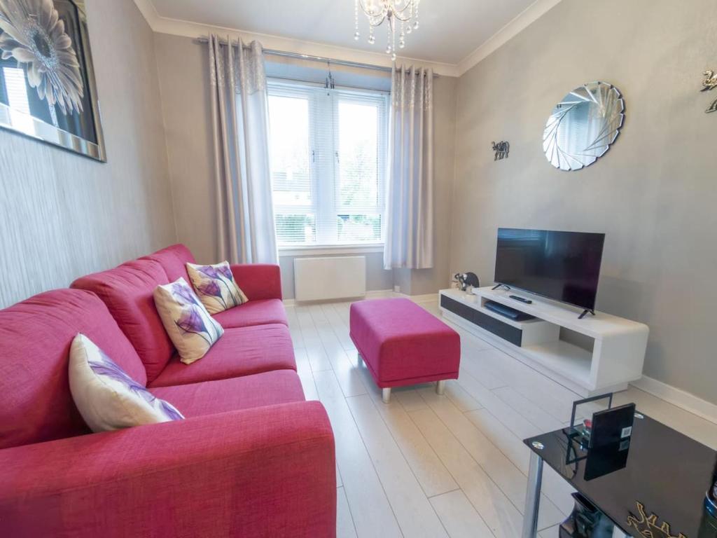 un salon avec un canapé rouge et une télévision dans l'établissement Central Renfrew 1BR Apt, à Renfrew