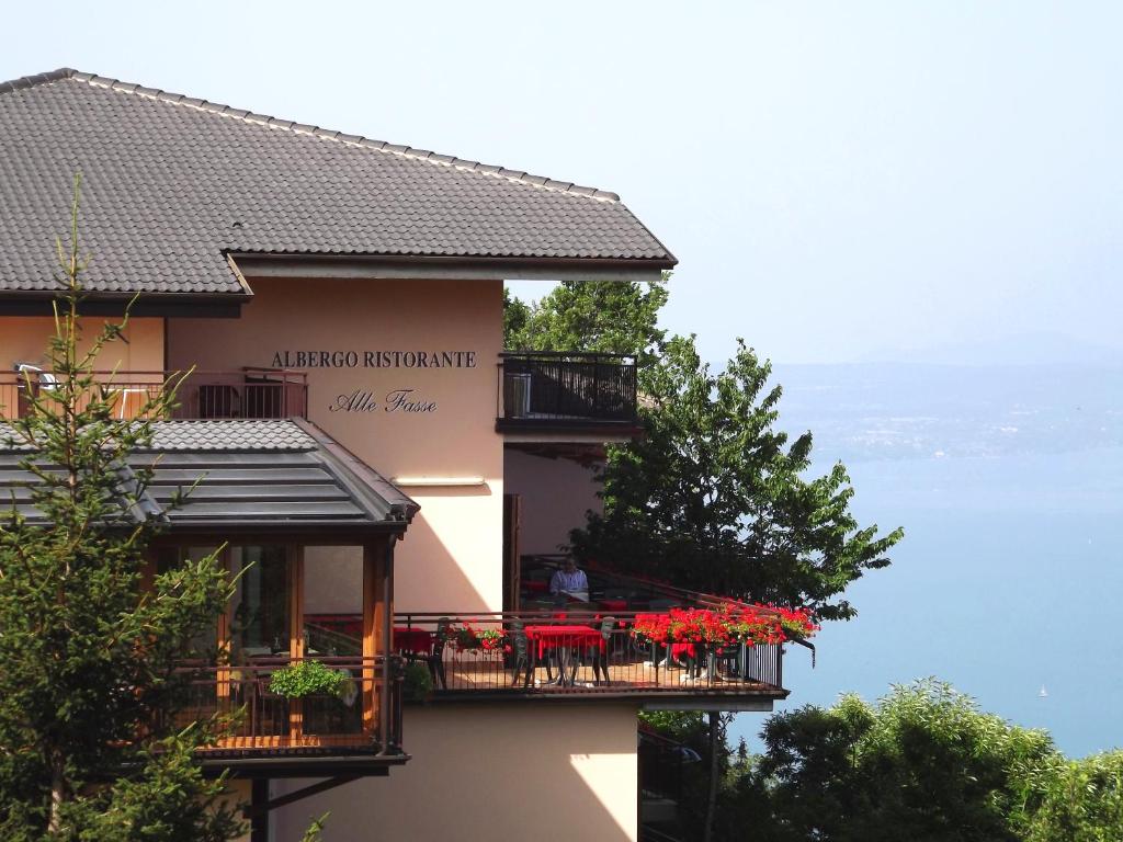 een gebouw met rode tafels en stoelen op een balkon bij Albergo Alle Fasse in Brenzone sul Garda