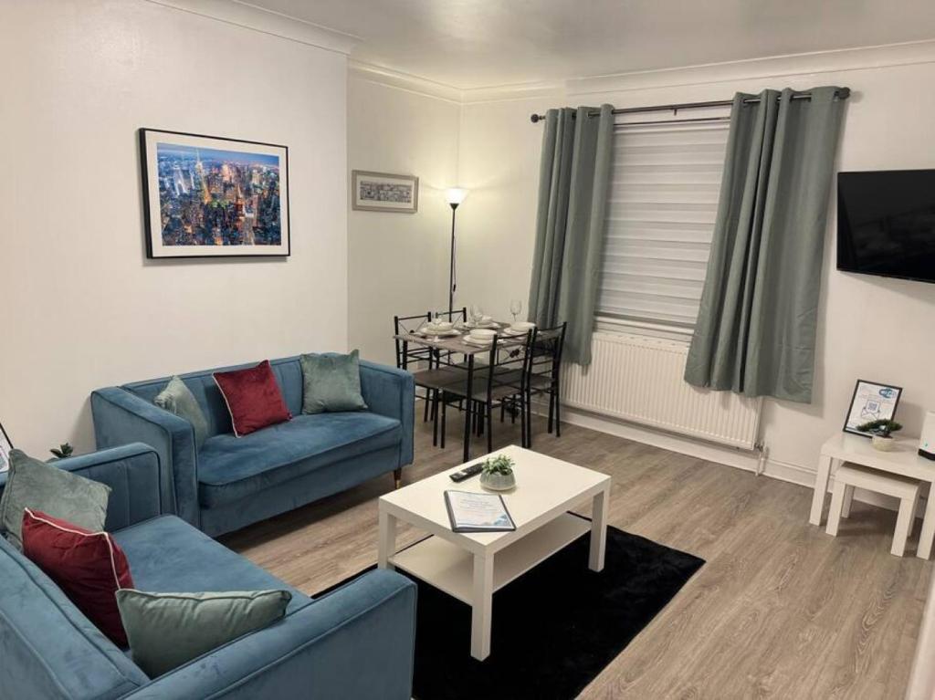 un salon avec un canapé bleu et une table dans l'établissement Stylish 2BR in Renfrew, à Renfrew