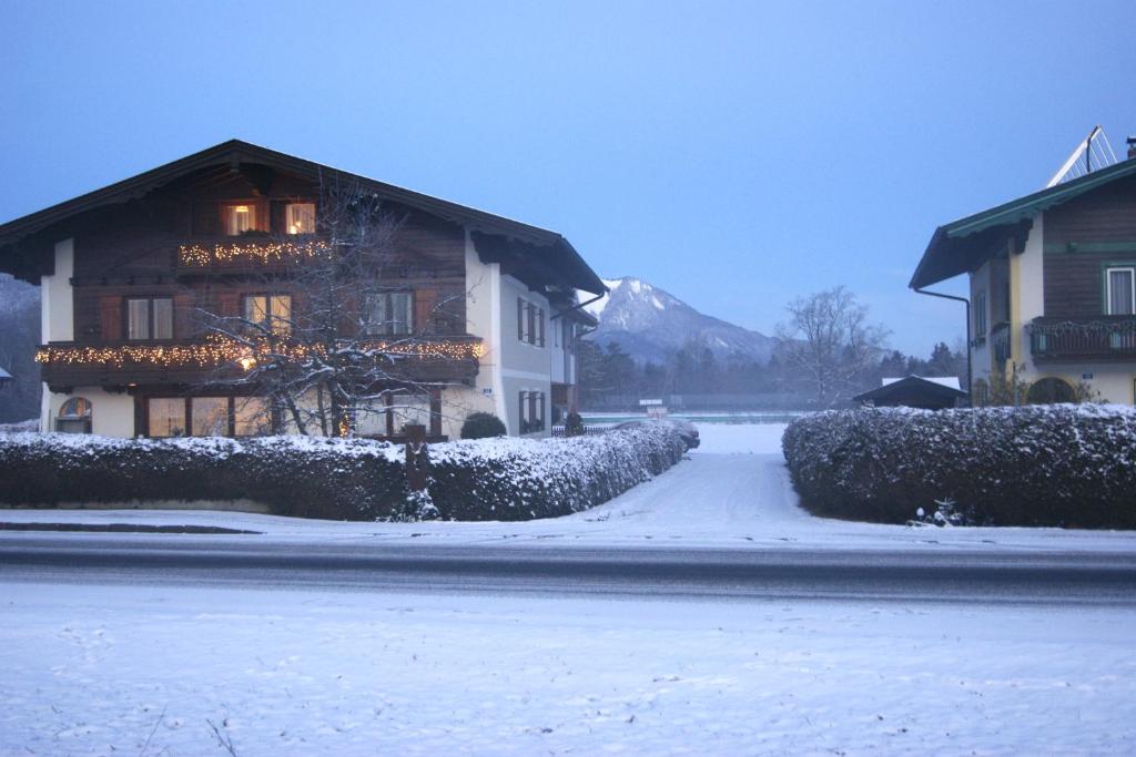 a building with snow on the ground next to a street at Abis Ferienwohnung Salzkammergut in Strobl