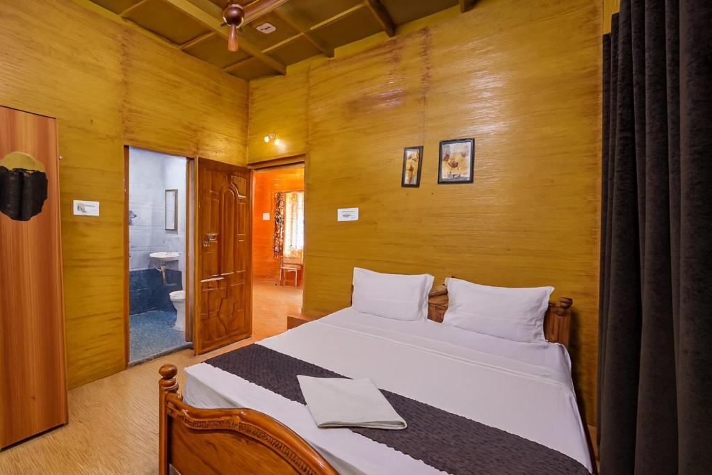 a bedroom with a bed with a wooden wall at HolidayZ by Stayz Royale in Yercaud - Misty Woody Stay in Yercaud