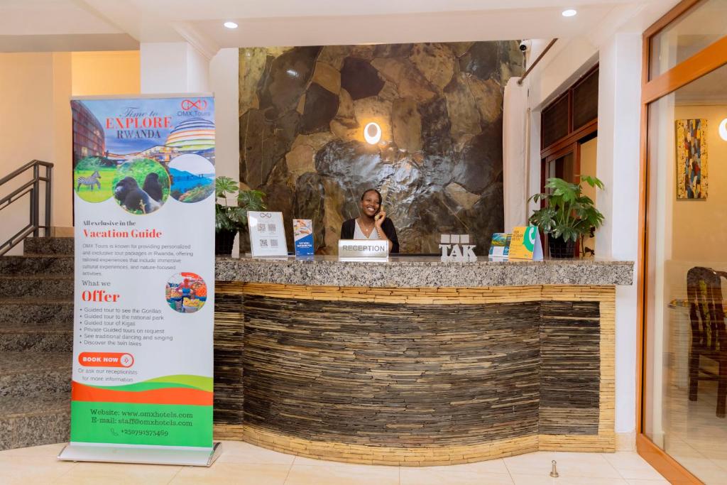 a woman is sitting at a counter in a restaurant at OMX Hotel Kimihurura in Kigali