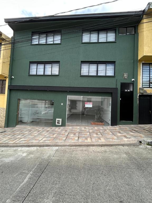 a large green building with two garage doors at Casa Vernazza in Manizales