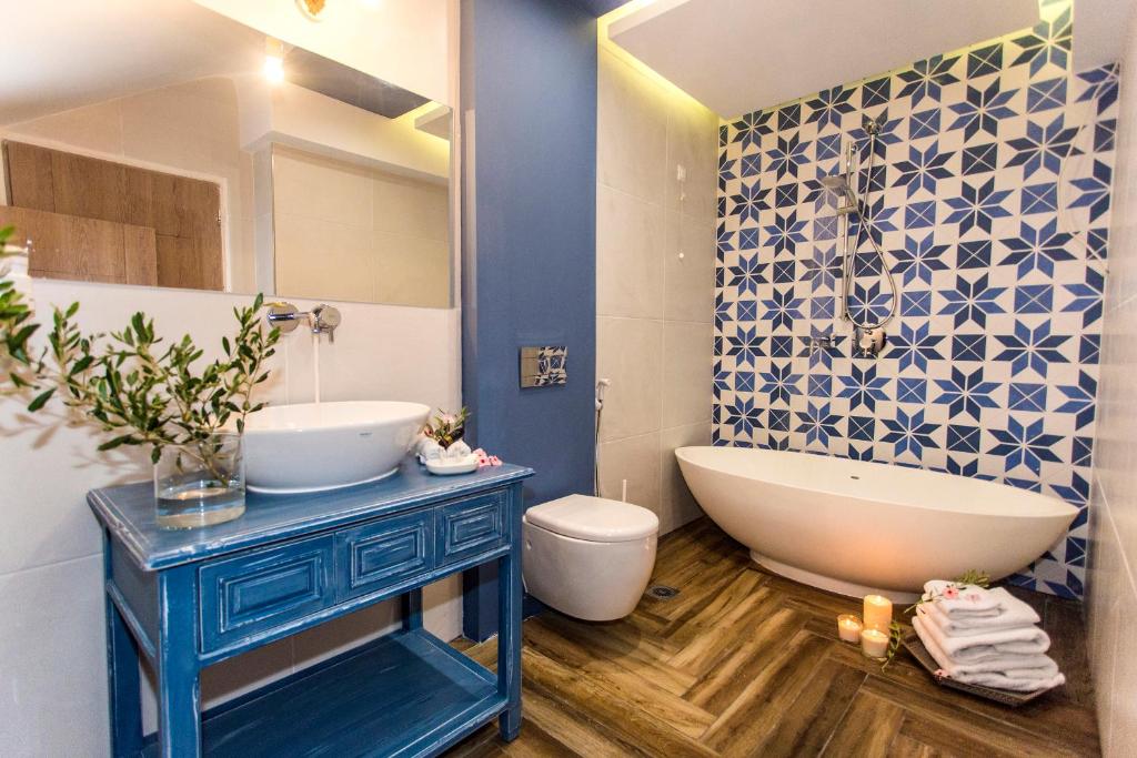 a bathroom with a tub and a sink and a toilet at Golden Bay Suites & Maisonettes in Parga