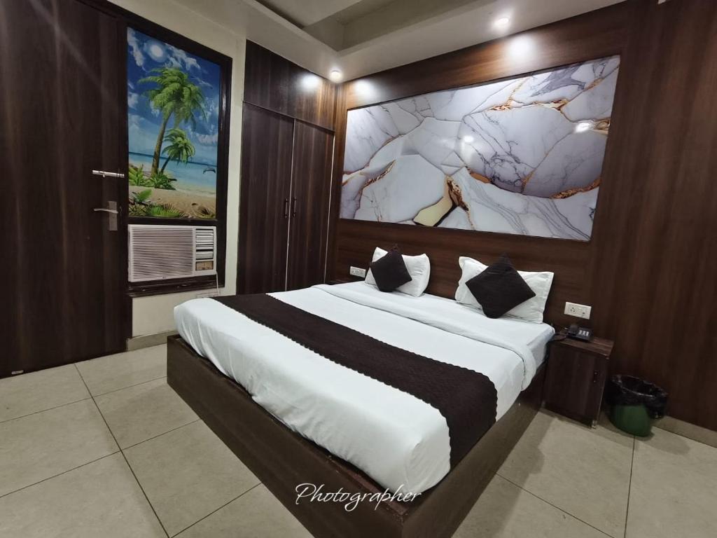 a bedroom with a large bed with a painting on the wall at Hotel Blu Bird in New Delhi