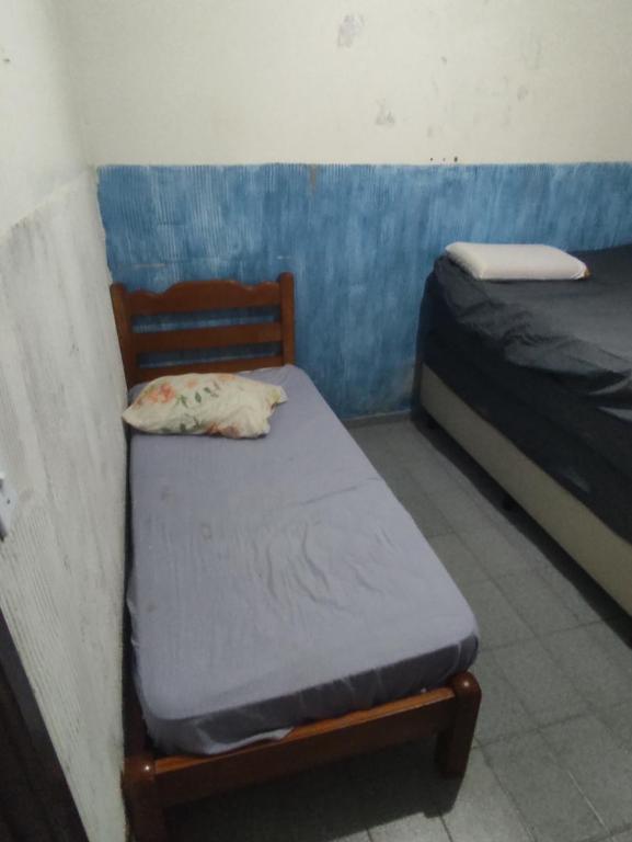ein kleines Zimmer mit 2 Betten und einem Stuhl in der Unterkunft Casa Tupy próxima a praia e restaurantes in Praia Grande