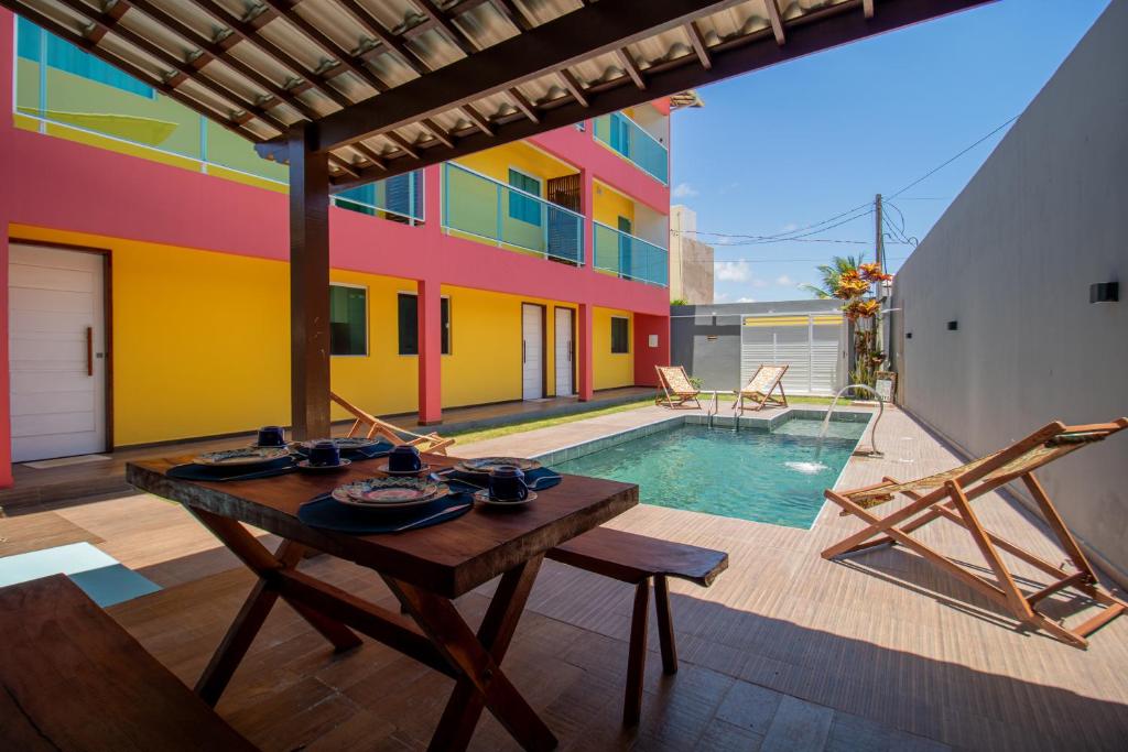 a patio with a table and a swimming pool at Zen Spa Houses in São Miguel dos Milagres