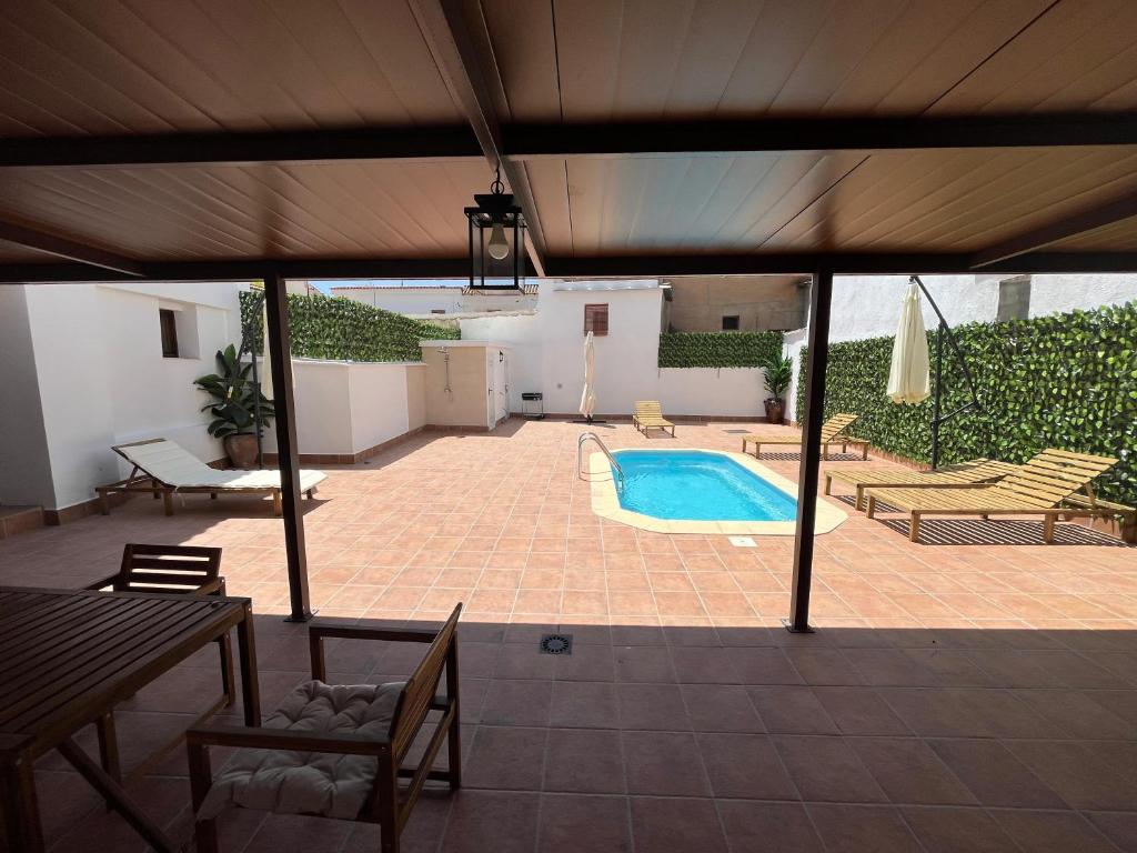eine Terrasse mit einem Pool, einem Tisch und Stühlen in der Unterkunft Alojamientos El Carmen in Ugíjar