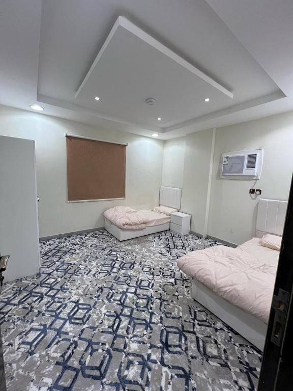 a room with two beds and a board in it at شقق فرسان العرب المخدومه in Umm Lujj