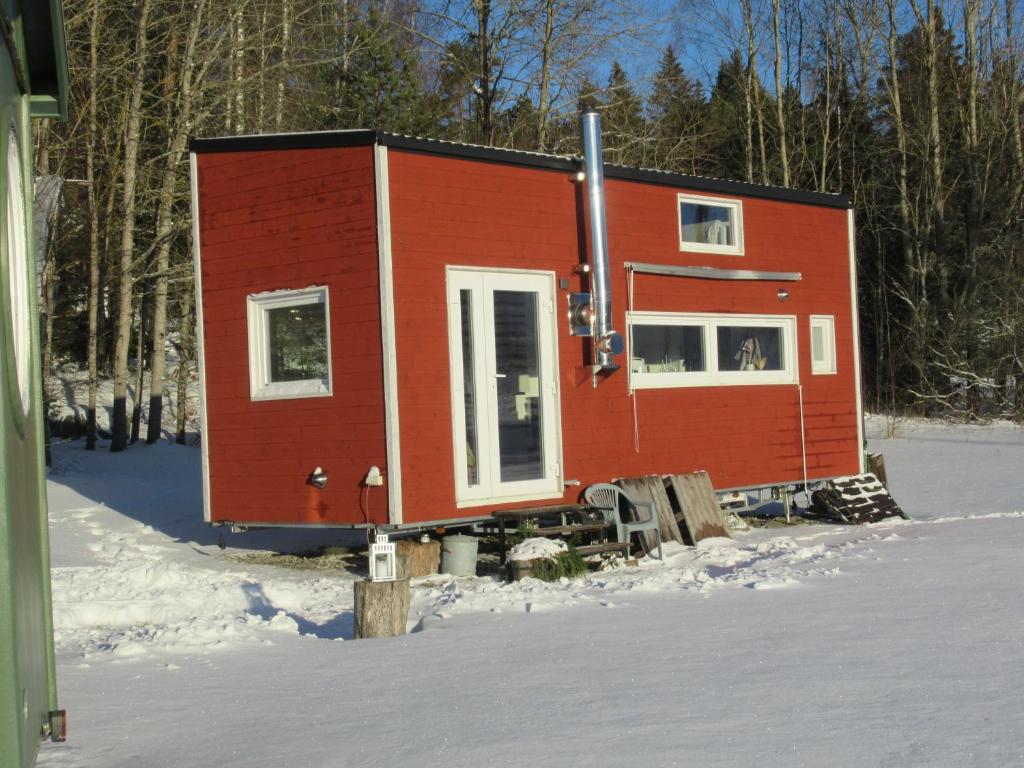 a red cabin in the snow in the woods at Stuga med bastu i naturen nära Stockholm in Järna