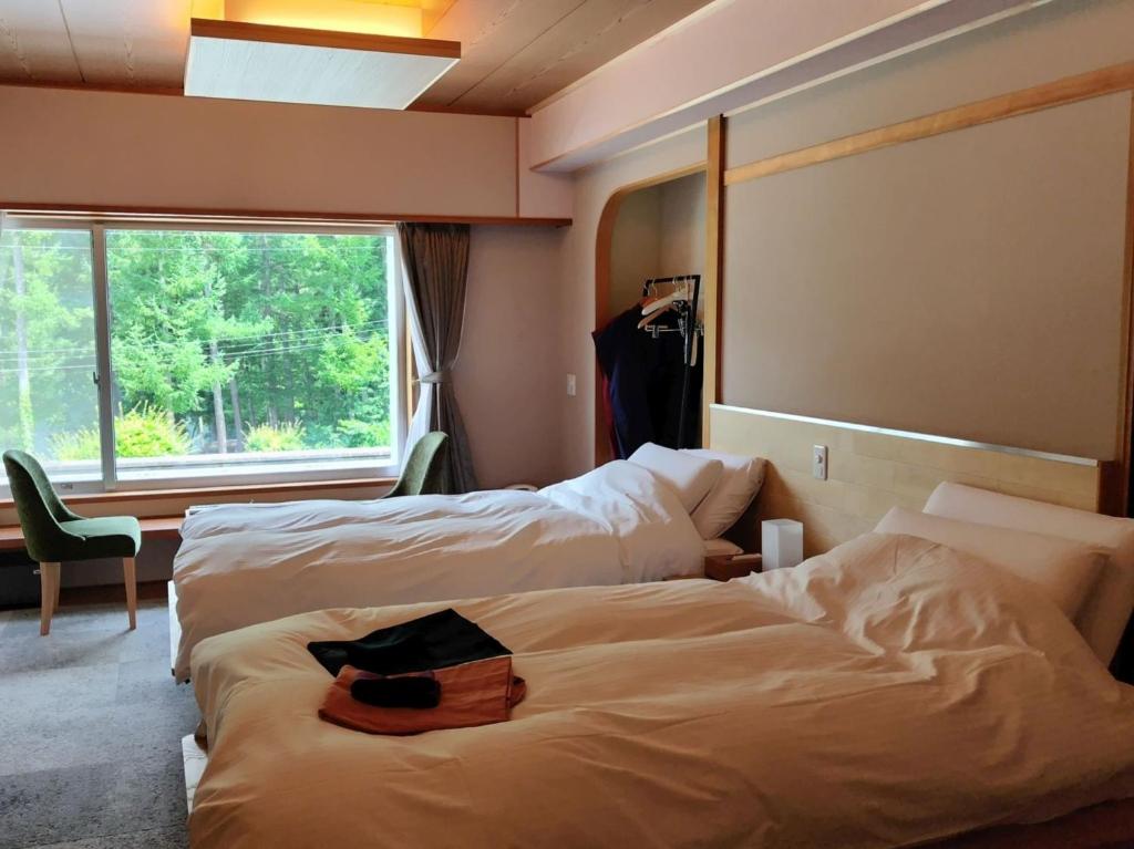 ein Hotelzimmer mit zwei Betten und einem Fenster in der Unterkunft HOKURYUKO HOTEL North NAGANO - Vacation STAY 44514v in Iiyama