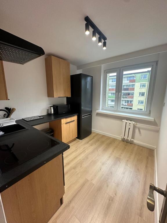 a kitchen with a black refrigerator and a large window at Nocleg Słupsk - Kwatera do 5 osób Kuchnia TV WiFi in Słupsk