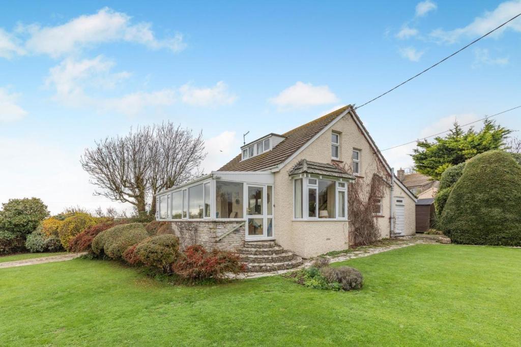 ein Haus mit einem grünen Rasen davor in der Unterkunft Cornerways in Worth Matravers