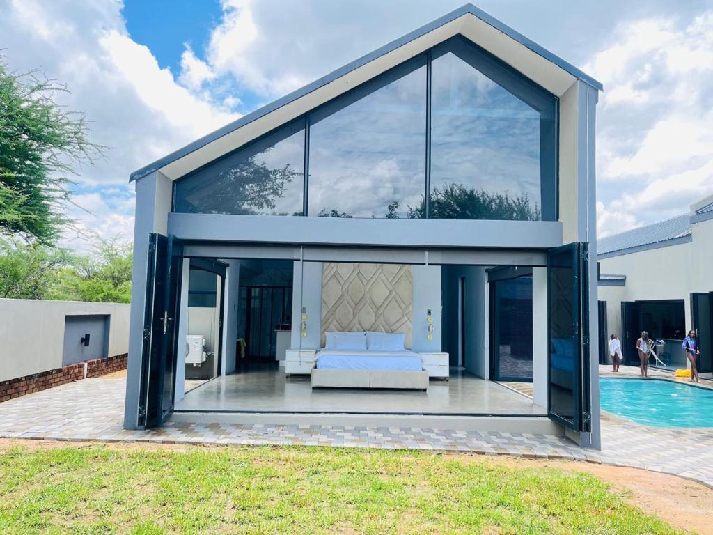 een groot glazen huis met een bank en een zwembad bij Kambula Villa 374 Euphoria in Mookgophong