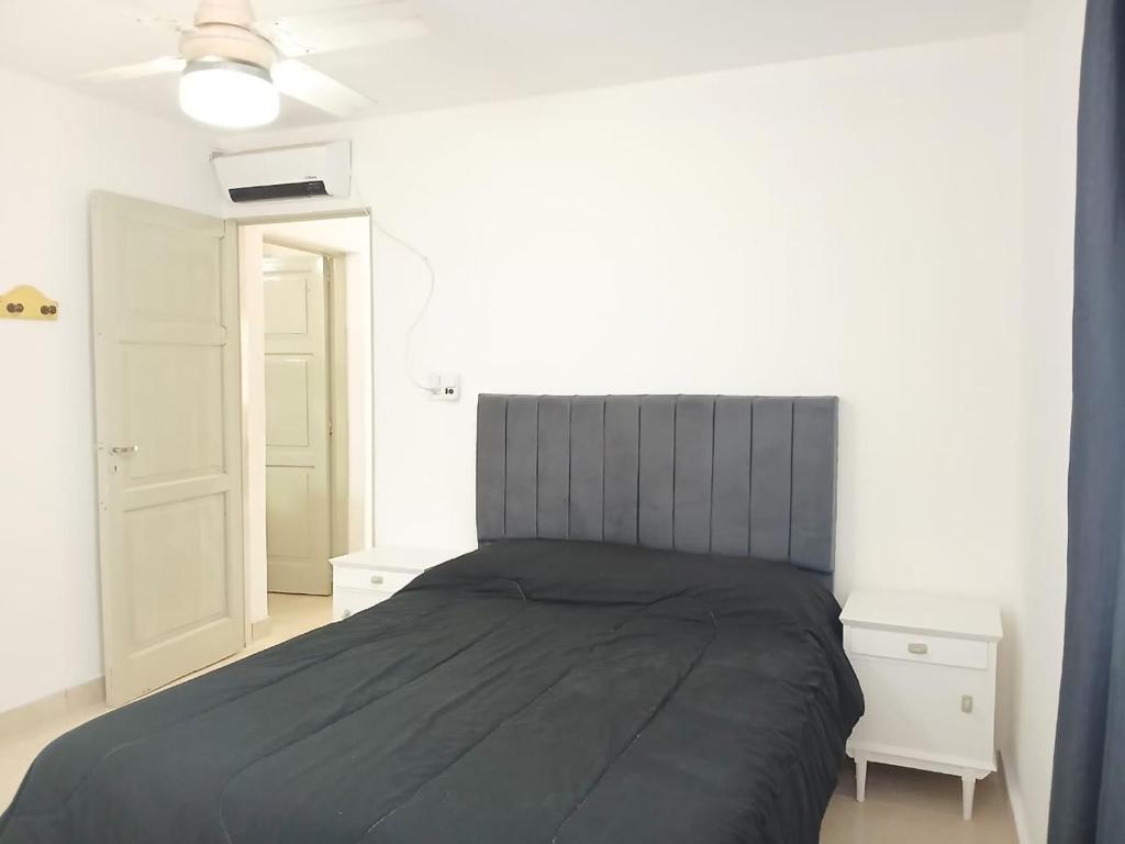 1 dormitorio con cama negra y pared blanca en Villa Carrizal, en Ciudad Lujan de Cuyo