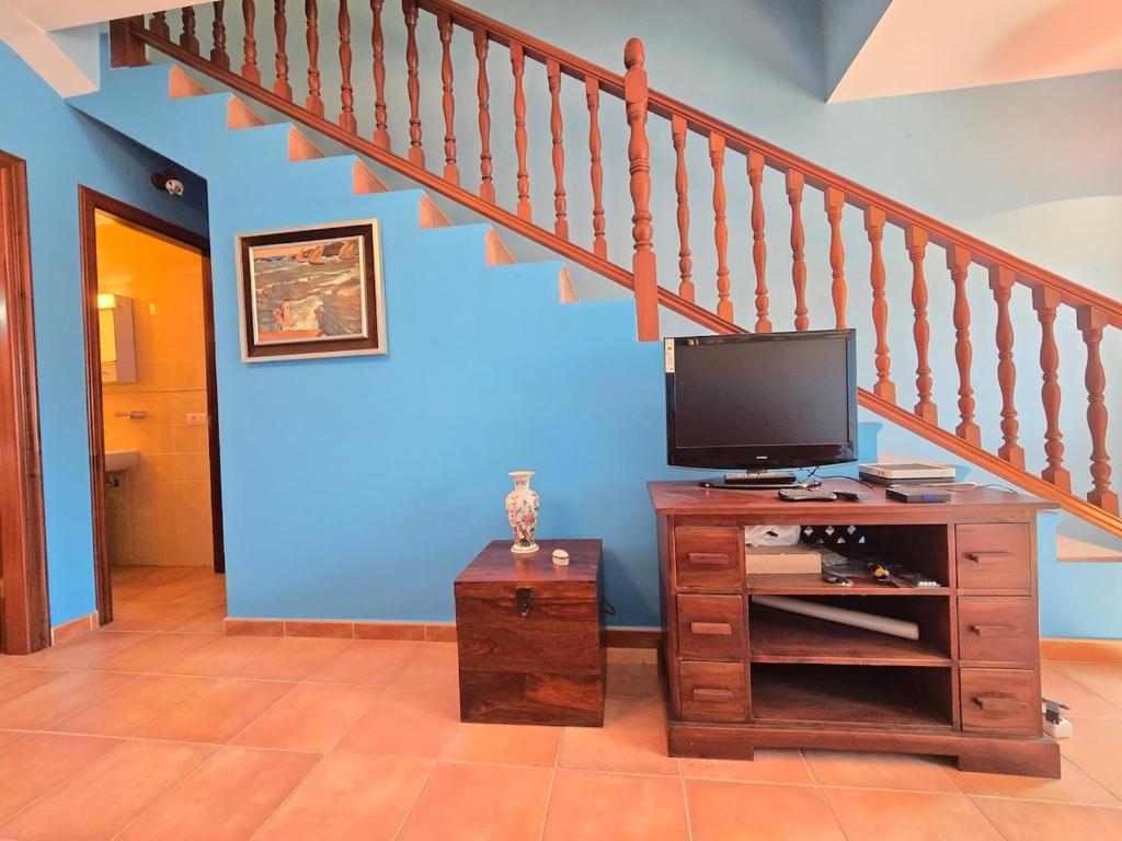 ein Wohnzimmer mit Fernseher und Treppe in der Unterkunft VV Zumacal La Palma in San Antonio