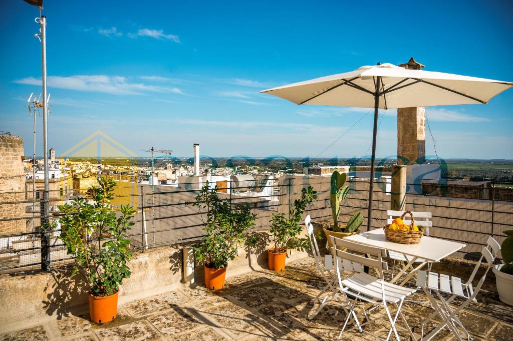 eine Terrasse mit Sonnenschirm und Tisch und Stühlen in der Unterkunft [Borgo Antico-Centro Storico] Casa Ventosa in Oria