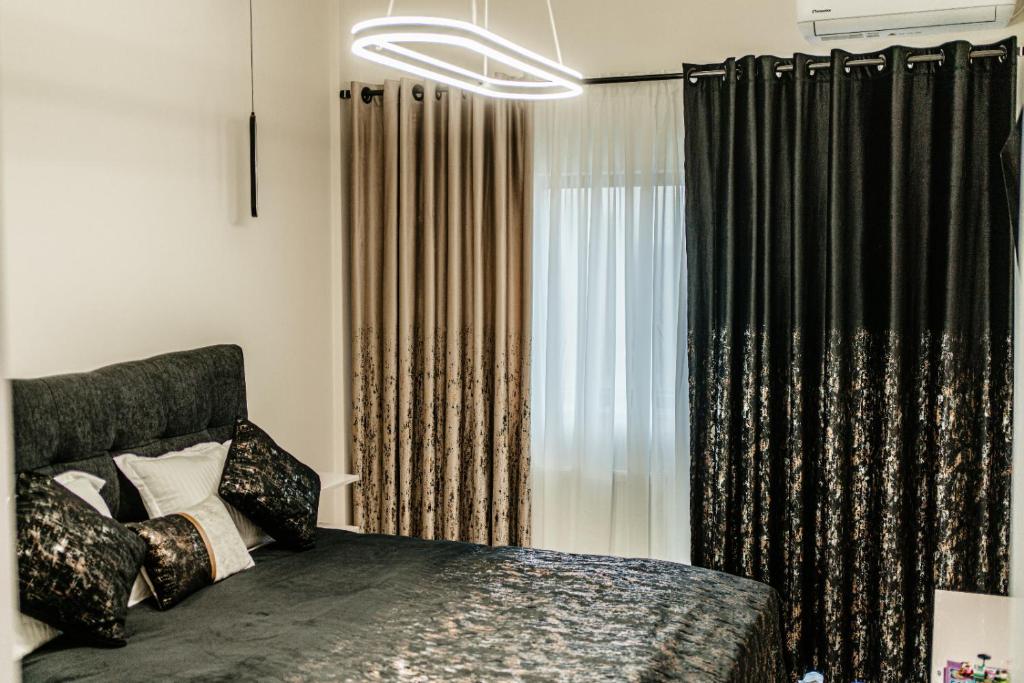 a bedroom with a bed and a window with curtains at Jessica luxury Apartament in Curtea de Argeş