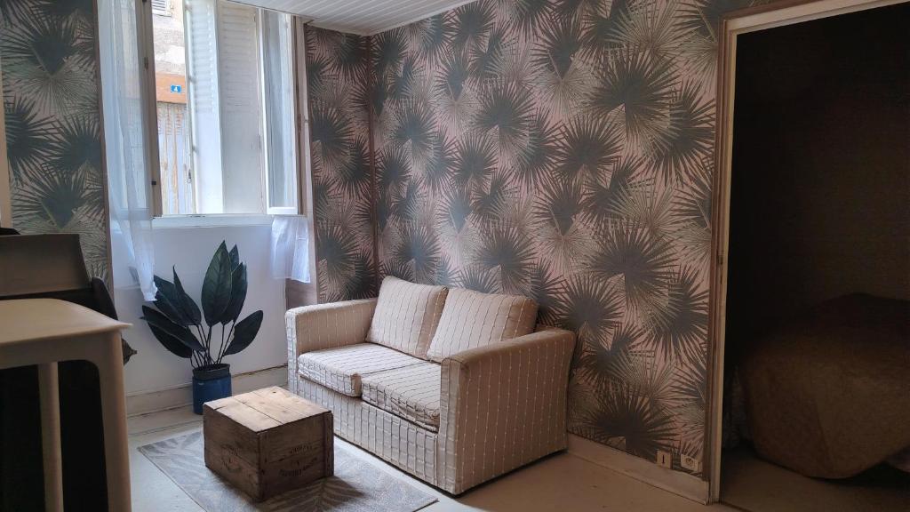 ein Wohnzimmer mit einem Stuhl und einem Spiegel in der Unterkunft À louer Charmant T2 en rez-de-chaussée à Châteaumeillant in Châteaumeillant